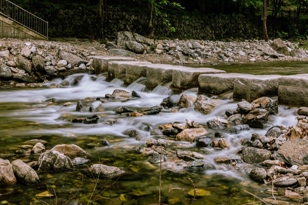 Stepping stones crossing a shallow river. Cover image for Touch the Stone and Cross the River: Running a Market You Cannot Model First.
