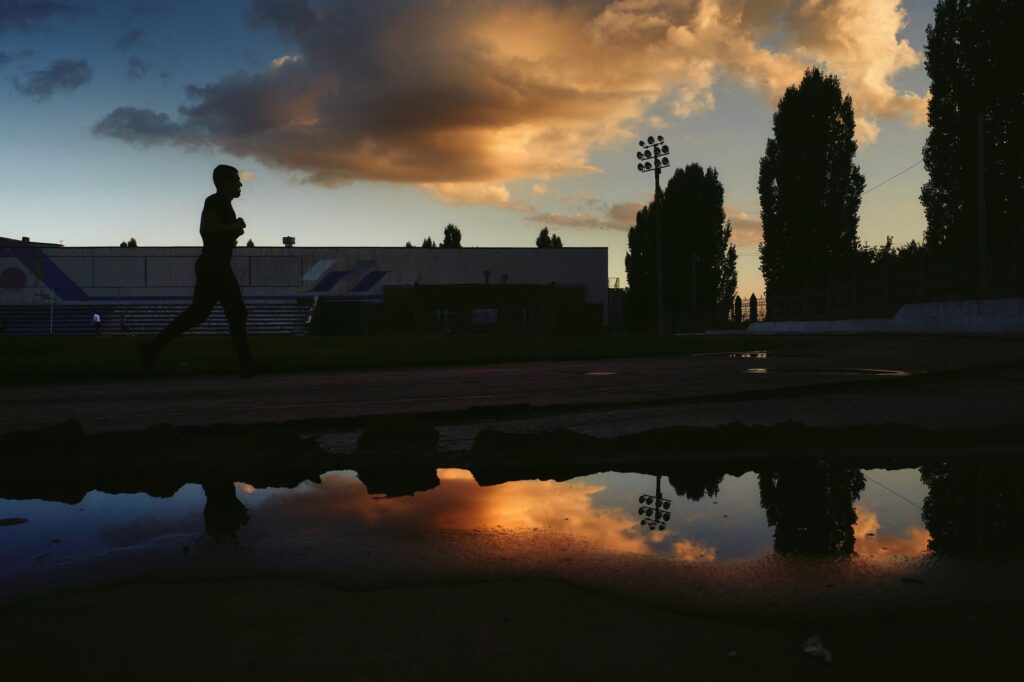 Runner on an athletics track at sunrise. Cover image for I Didn't Run to Role Model Quitting.