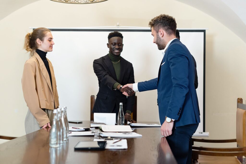 Handshake across a conference table. Cover image for They Would Never Give Me the Money If It Didn't Work.