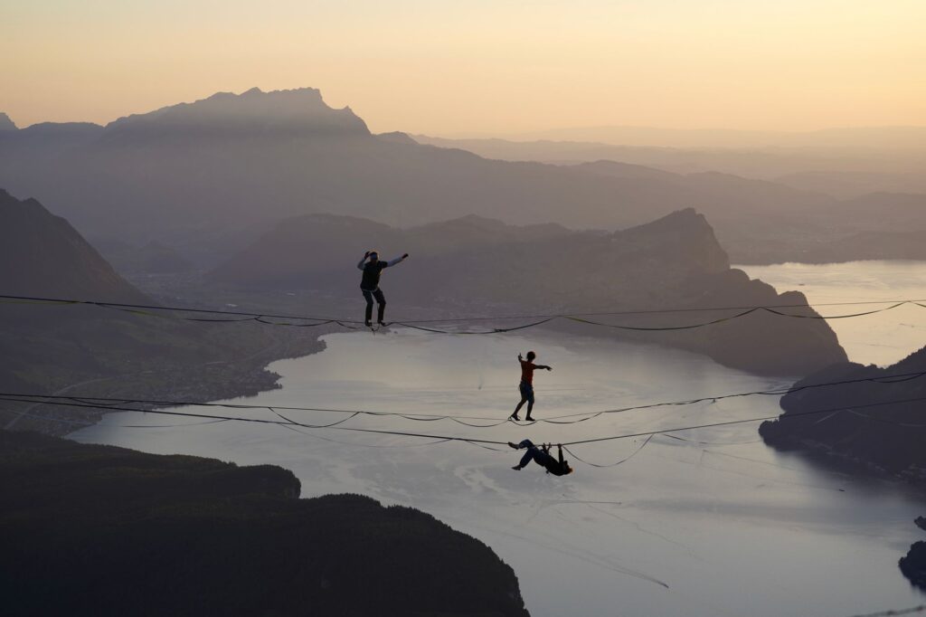 Highline walkers above a lake at sunset. Cover image for Six M2030 Growth Paradoxes.